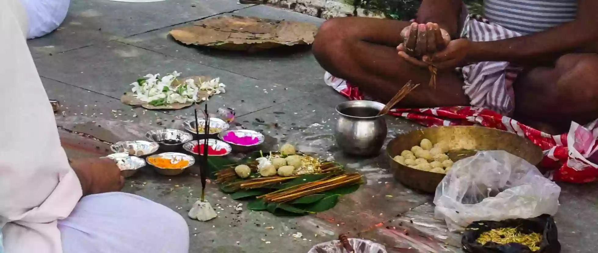 A pandit preparing pindas and offerings on a leaf plate at the ghat