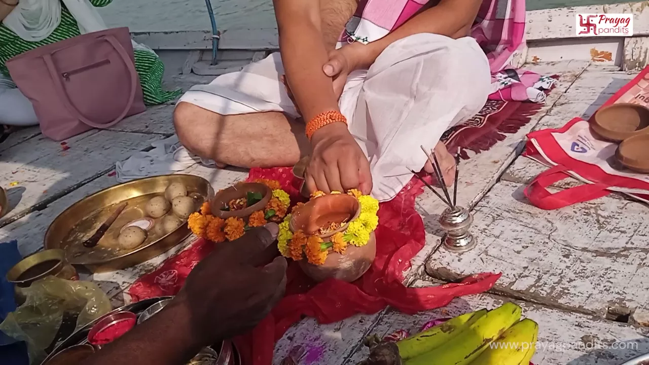 A couple performing Asthi Visarjan from a boat at the Triveni Sangam